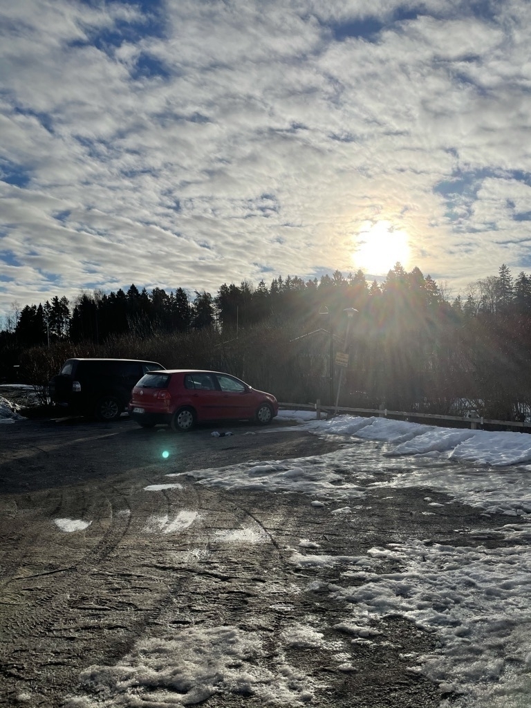sun shining over a parking lot, some snow on the ground