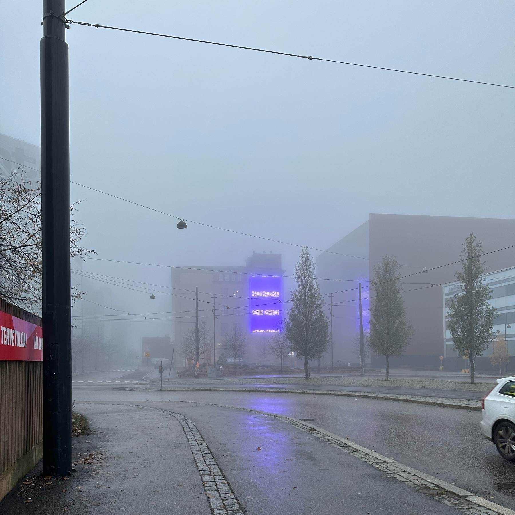 end of a building with neon lights glowing through fog