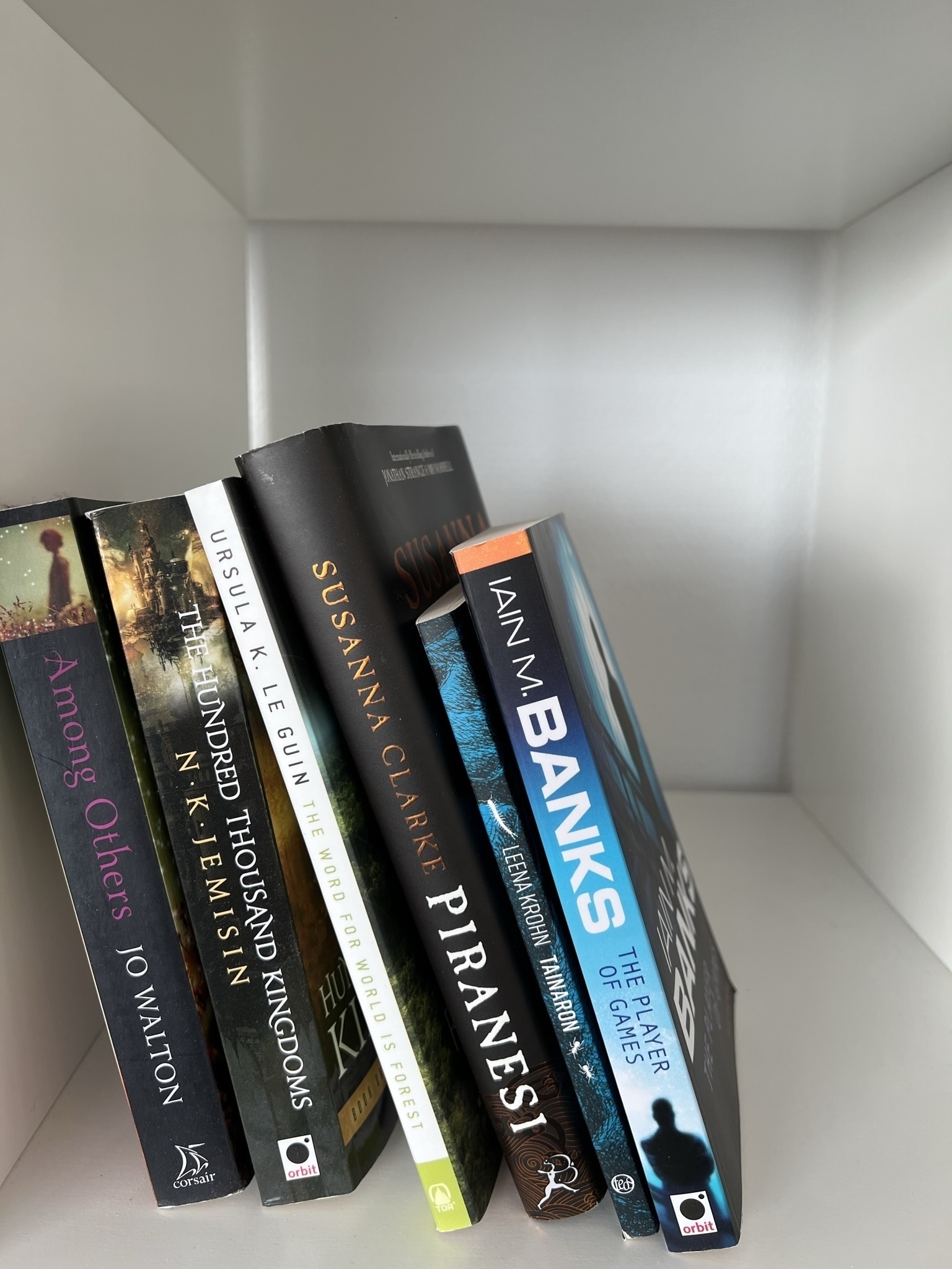 Bookshelf with: Among Others by Jo Walton, The Hundred Thousand Kingdoms by N.K. Jemisin, Ursula K. Le Guin’s The Word for World is Tree, Tainaron by Leena Krohn, and The Player of Games by Iain M. Banks